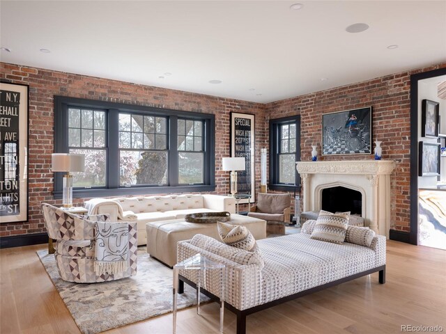 living room featuring wood finished floors, brick wall, and a healthy amount of sunlight