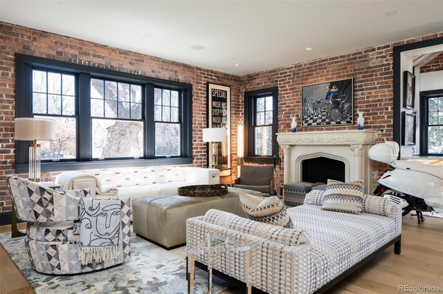 living room with wood finished floors, brick wall, and a fireplace