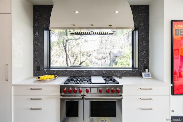kitchen with white cabinets, range with two ovens, tasteful backsplash, and light countertops