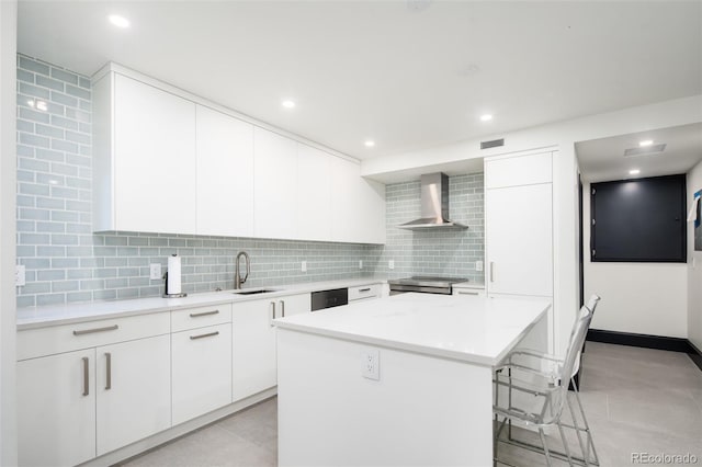 kitchen featuring a center island, tasteful backsplash, a sink, a breakfast bar, and wall chimney exhaust hood