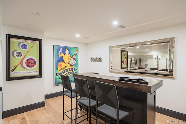 bar with recessed lighting, baseboards, a bar, and light wood finished floors