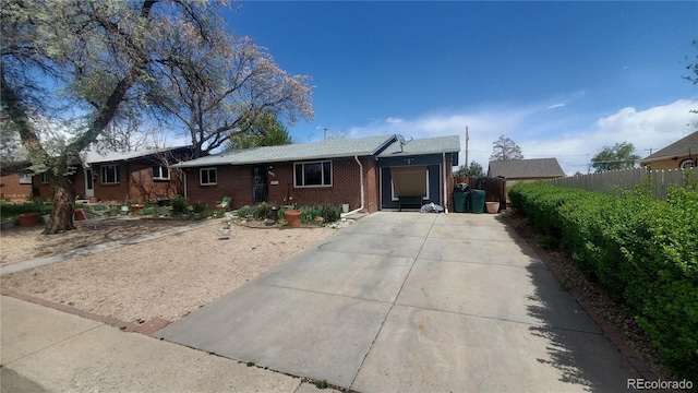 ranch-style house with fence, driveway, and brick siding