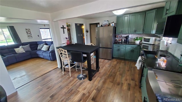 kitchen featuring green cabinetry, freestanding refrigerator, and range