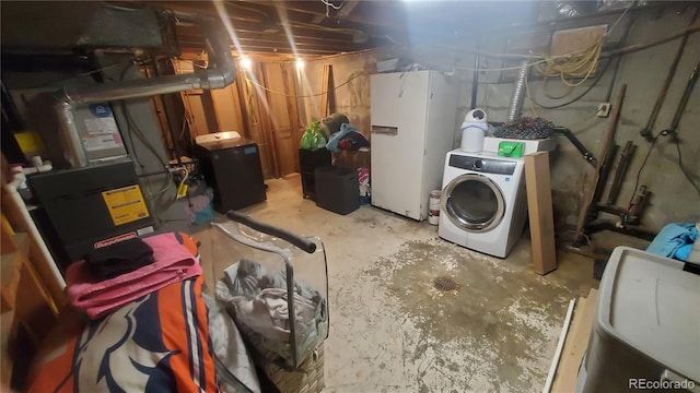 unfinished basement with washer / clothes dryer and freestanding refrigerator