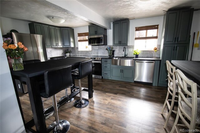7620 Hooker St, Westminster, CO 80030 - kitchen with stainless steel appliances, a sink, dark countertops, decorative backsplash, and dark wood finished floors