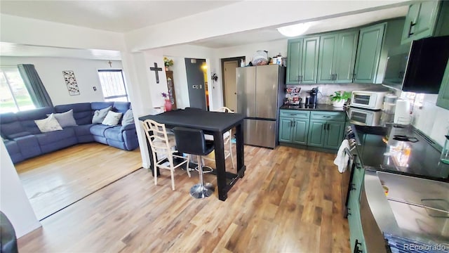 7620 Hooker St, Westminster, CO 80030 - kitchen featuring green cabinets, freestanding refrigerator, dark countertops, light wood-type flooring, and open floor plan