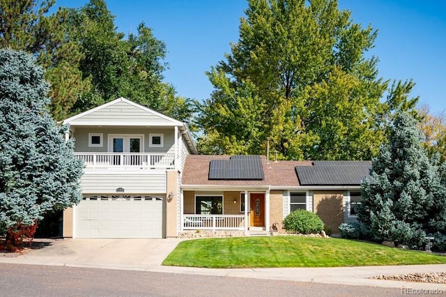 view of front facade with a garage, covered porch, a front yard, and solar panels