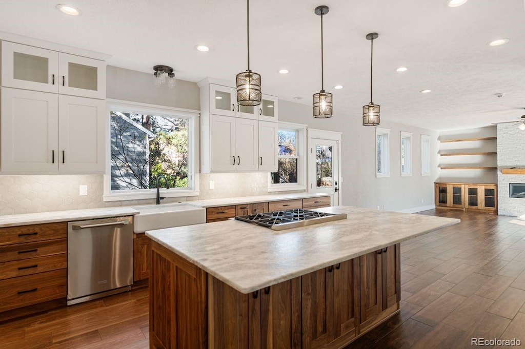 kitchen featuring a center island, a stone fireplace, sink, appliances with stainless steel finishes, and white cabinetry