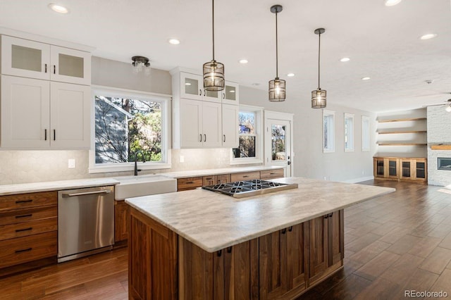 kitchen featuring a center island, a stone fireplace, sink, appliances with stainless steel finishes, and white cabinetry