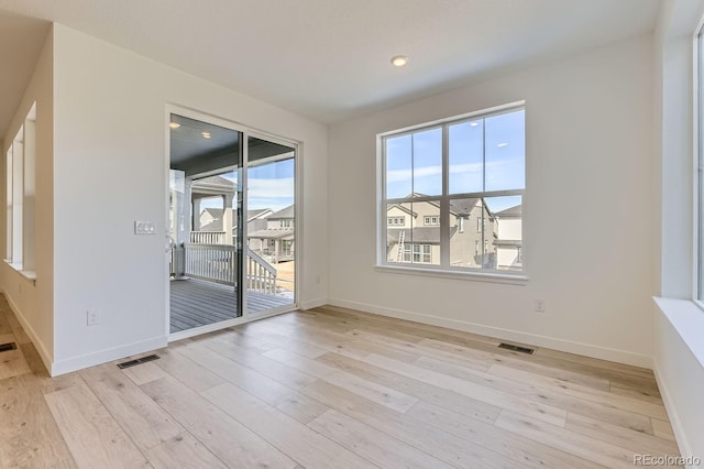 empty room featuring light wood finished floors, baseboards, and visible vents