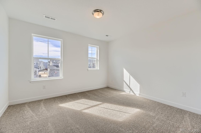 carpeted spare room with visible vents and baseboards