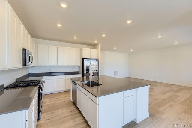 kitchen featuring light wood finished floors, dark countertops, recessed lighting, appliances with stainless steel finishes, and a sink