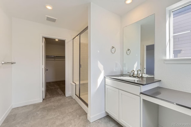 bathroom with recessed lighting, vanity, visible vents, a shower stall, and a walk in closet