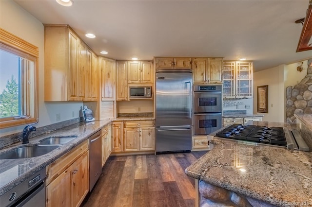 kitchen with built in appliances, light stone countertops, sink, and dark wood-type flooring