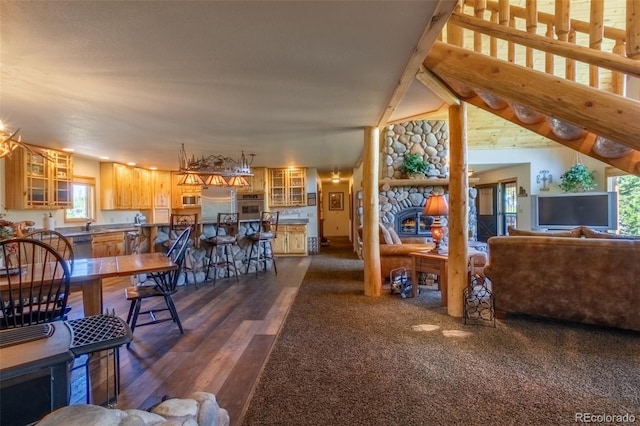 living room featuring a stone fireplace and dark wood-type flooring