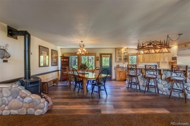 dining space featuring a textured ceiling, dark wood-type flooring, a wood stove, and a notable chandelier