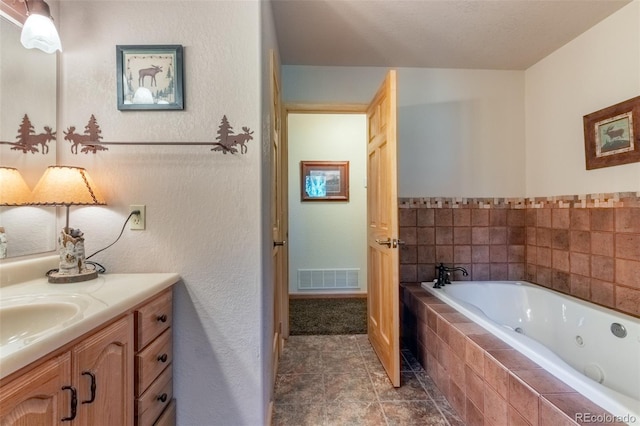 bathroom with vanity and tiled bath