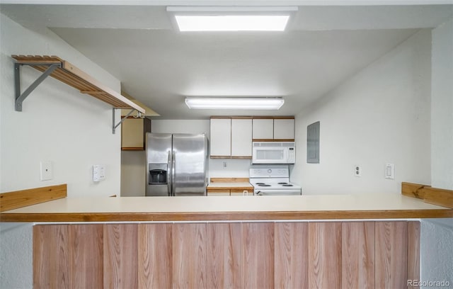 kitchen with a peninsula, light countertops, and white appliances