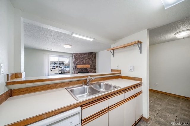 kitchen featuring a sink, open shelves, white cabinets, a textured ceiling, and a stone fireplace