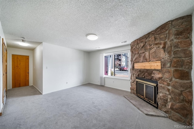 unfurnished living room with baseboards, a stone fireplace, carpet flooring, and visible vents