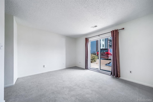 carpeted empty room featuring a textured ceiling, visible vents, and baseboards
