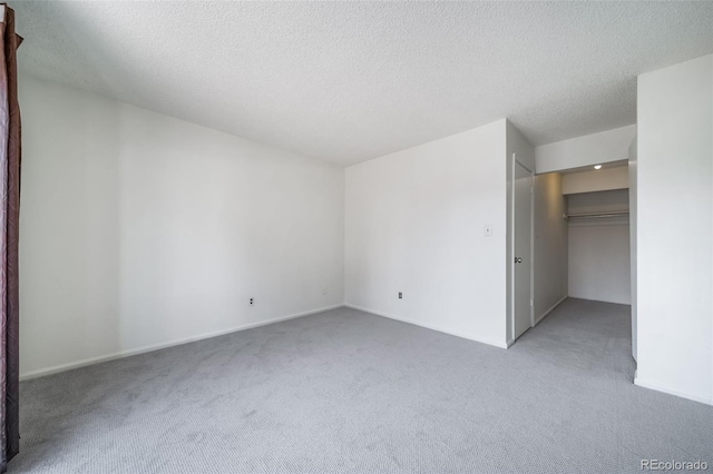 unfurnished bedroom with carpet flooring, a closet, a textured ceiling, and a walk in closet