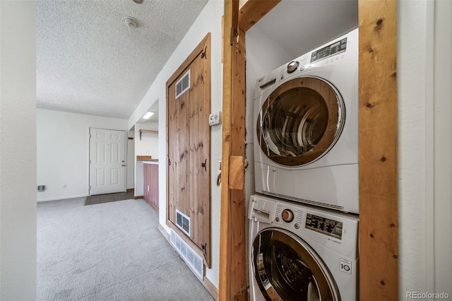 washroom featuring a textured ceiling, carpet, visible vents, laundry area, and stacked washer / drying machine