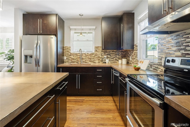 3743 N Yates St, Denver, CO 80212 - kitchen with appliances with stainless steel finishes, ventilation hood, light wood-style flooring, tasteful backsplash, and hanging light fixtures