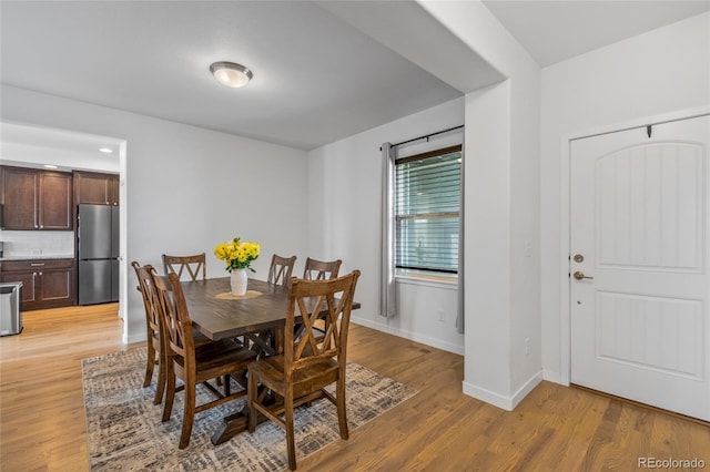 dining area featuring light wood-style flooring and baseboards