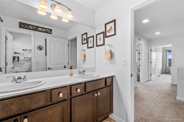 bathroom with double vanity, baseboards, toilet, and a sink