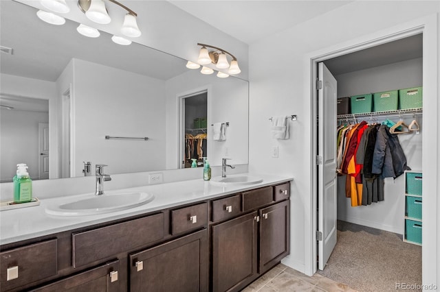 bathroom featuring visible vents, a sink, a spacious closet, and double vanity