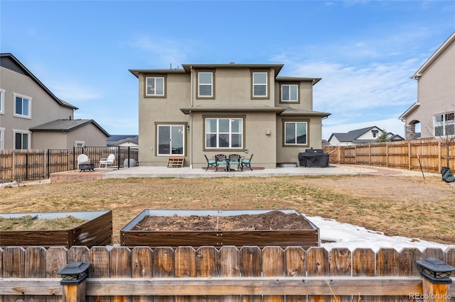 back of house with a fenced front yard, a garden, a patio, and stucco siding