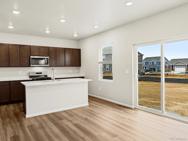 2728 73rd Avenue Ct, Greeley, CO 80634 - kitchen featuring stainless steel appliances, light wood-style flooring, dark brown cabinetry, light countertops, and a sink