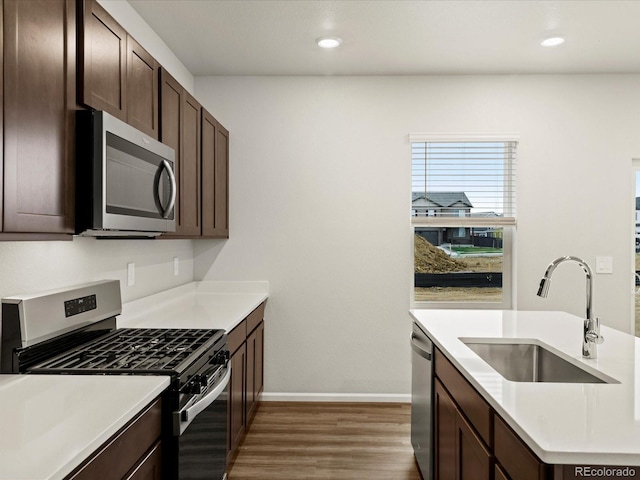 2728 73rd Avenue Ct, Greeley, CO 80634 - kitchen featuring stainless steel appliances, a sink, wood finished floors, dark brown cabinets, and baseboards