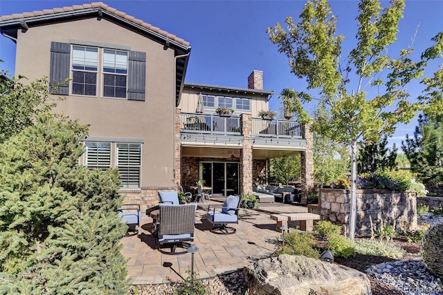 10553 Fairhurst Way, Highlands Ranch, CO 80126 - back of property featuring a balcony, an outdoor living space, a patio area, a chimney, and stucco siding