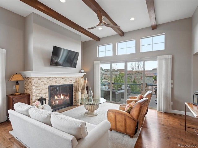 10553 Fairhurst Way, Highlands Ranch, CO 80126 - living room featuring beam ceiling, a glass covered fireplace, ceiling fan, hardwood / wood-style floors, and a high ceiling