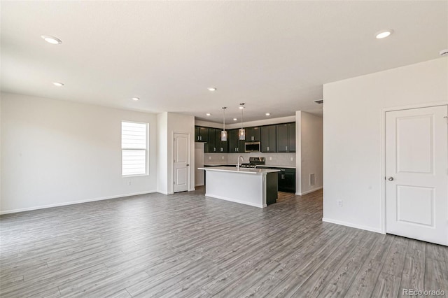 13322 E 110th Way, Commerce City, CO 80022 - kitchen with open floor plan, stainless steel microwave, an island with sink, wood finished floors, and recessed lighting