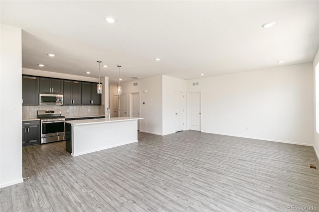 13322 E 110th Way, Commerce City, CO 80022 - kitchen featuring stainless steel appliances, light wood finished floors, open floor plan, tasteful backsplash, and recessed lighting