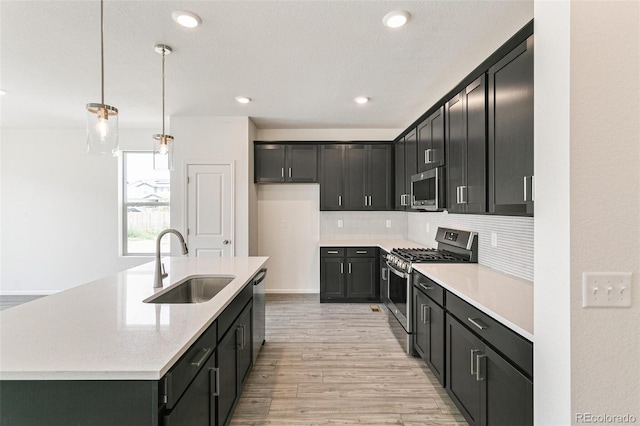 13322 E 110th Way, Commerce City, CO 80022 - kitchen with appliances with stainless steel finishes, light wood finished floors, light countertops, decorative backsplash, and a center island with sink