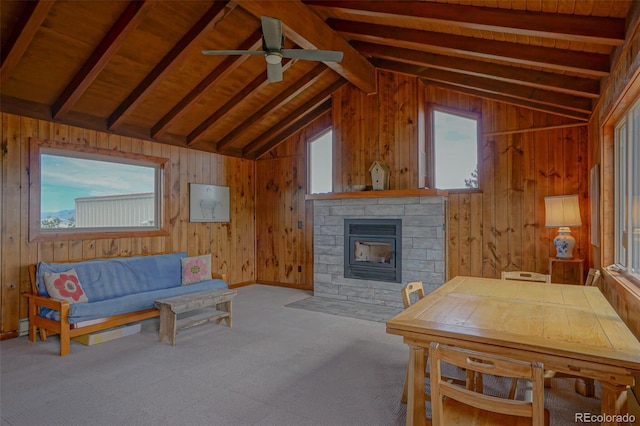 carpeted living room with ceiling fan, a fireplace, lofted ceiling with beams, and a wealth of natural light