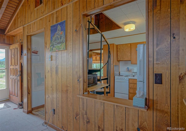 exterior space featuring wood walls, white appliances, light colored carpet, and vaulted ceiling