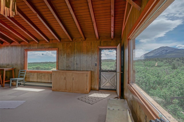 unfurnished sunroom with wood ceiling, a mountain view, baseboard heating, and a healthy amount of sunlight