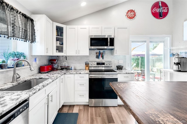12175 Birch St, Thornton, CO 80241 - kitchen with appliances with stainless steel finishes, vaulted ceiling, decorative backsplash, wood finished floors, and white cabinets