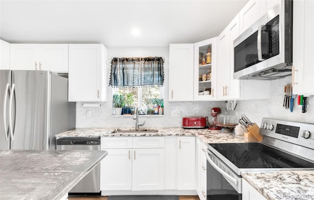 12175 Birch St, Thornton, CO 80241 - kitchen with stainless steel appliances, white cabinets, backsplash, light stone counters, and glass insert cabinets