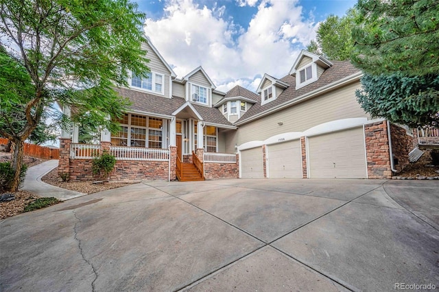 7506 Urban Ct, Arvada, CO 80005 - view of front of home with stone siding, a porch, driveway, and a garage
