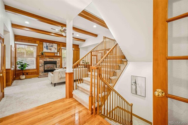7506 Urban Ct, Arvada, CO 80005 - staircase featuring wood finished floors, a stone fireplace, ceiling fan, beam ceiling, and recessed lighting