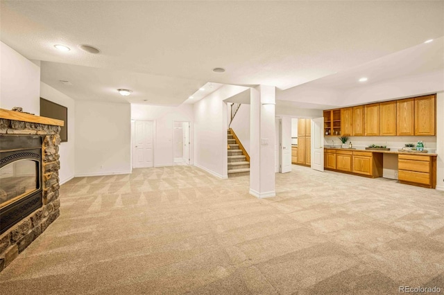 7506 Urban Ct, Arvada, CO 80005 - unfurnished living room with light colored carpet, stairway, a stone fireplace, and recessed lighting