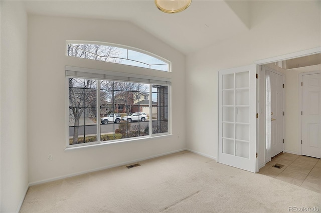 carpeted empty room featuring baseboards, visible vents, and vaulted ceiling