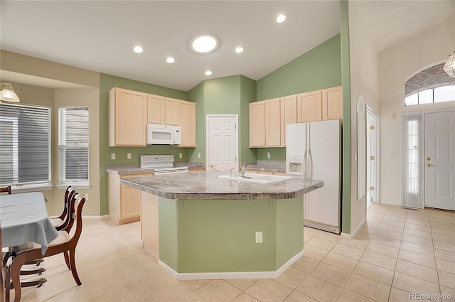 kitchen featuring light tile patterned floors, light countertops, a sink, an island with sink, and white appliances