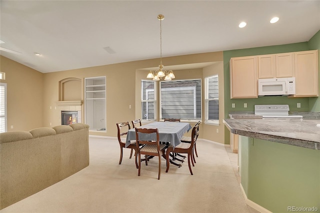 dining space with lofted ceiling, light colored carpet, a tiled fireplace, an inviting chandelier, and baseboards